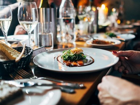 Plated dish and glasses of white wine on a restaurant table