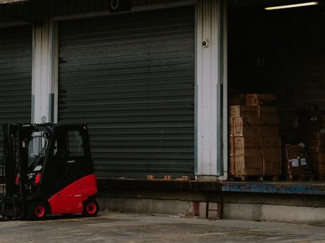 Red forklift at a warehouse loading dock with stacked boxes