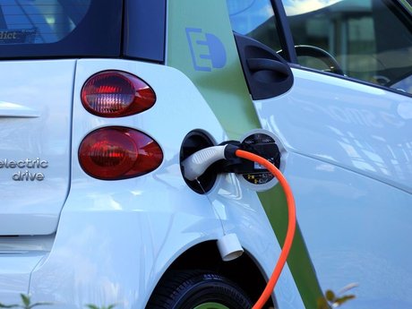 Electric car being charged with an orange charging cable
